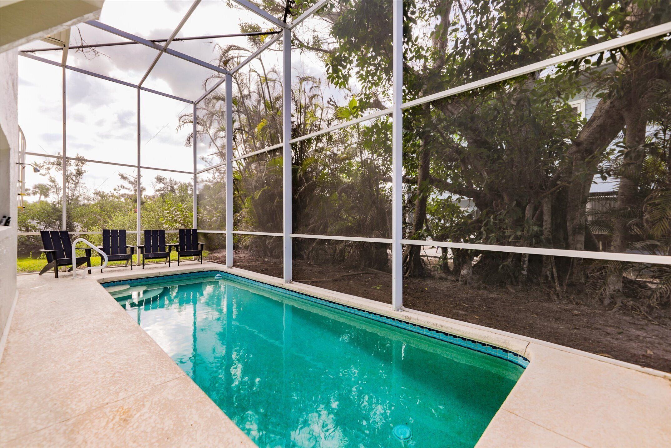 Une piscine intérieure offrant une vue dégagée sur les arbres environnants et un espace abrité avec des chaises.