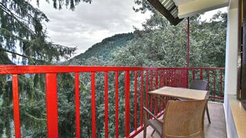 A balcony with a red railing, a table, and wicker chairs.