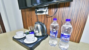 Eine Küchenzeile mit einer Kaffeemaschine, zwei Tassen und zwei Flaschen Aquafina Wasser auf einem Tablett.