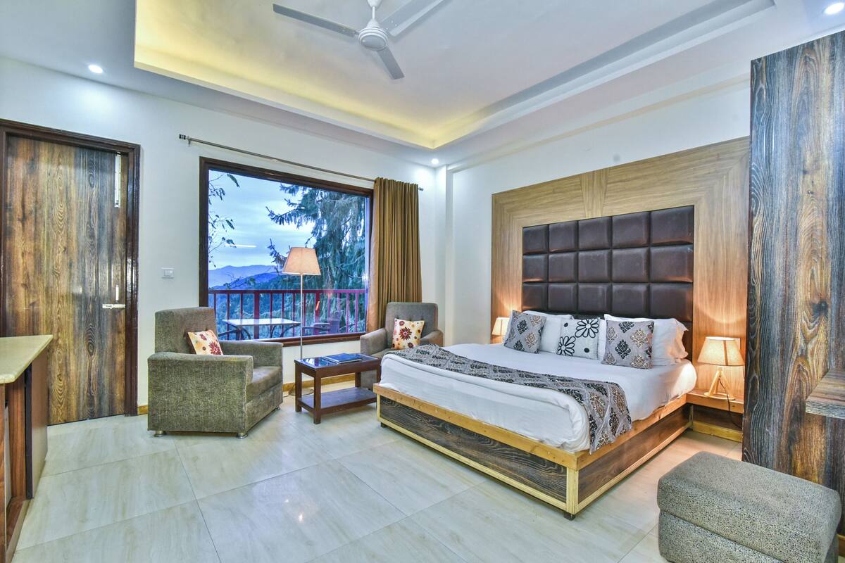 Un dormitorio moderno con una cama grande, dos sillones, una mesita y vistas al exterior.