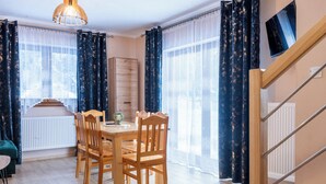 Un comedor con una mesa y sillas de madera, un radiador y un televisor montado en la pared.