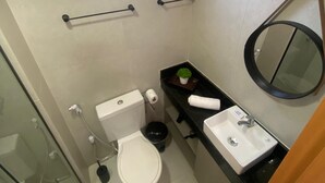 A compact bathroom with a toilet, sink, and a small window. - Flat 114 Centro Porto de Galinhas bLP (Ipojuca)