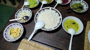 Una mesa con diversos platos y tazones de comida, incluyendo arroz y diferentes tipos de curry.