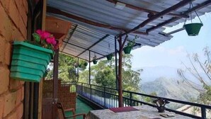 Un espacio al aire libre cubierto con una mesa, sillas, plantas en macetas y vistas a las montañas.