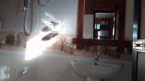 Un baño con un lavamanos blanco, un espejo y una ventana que da a vistas de árboles y un edificio.