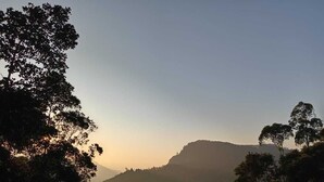 Un paisaje montañoso con una colina destacada en el centro, rodeado de vegetación densa.