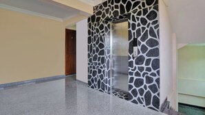 A hallway with a stone-patterned wall and a wooden door. - Family Castle Hotel & Restaurant (Thiruvananthapuram)