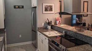 A modern kitchen with granite countertops, stainless steel appliances, and a backsplash. - Cottage Beneath the Branches in Wachesaw-golf/pool/beach (Murrells Inlet)