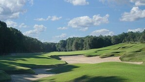 A golf course with sand bunkers, water hazards, and a forested background. - Cottage Beneath the Branches in Wachesaw-golf/pool/beach (Murrells Inlet)