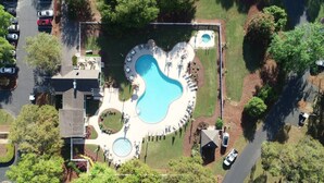 An aerial view of a residential area with a large swimming pool, multiple lounge chairs, and a small boat docked near the pool. - Cottage Beneath the Branches in Wachesaw-golf/pool/beach (Murrells Inlet)