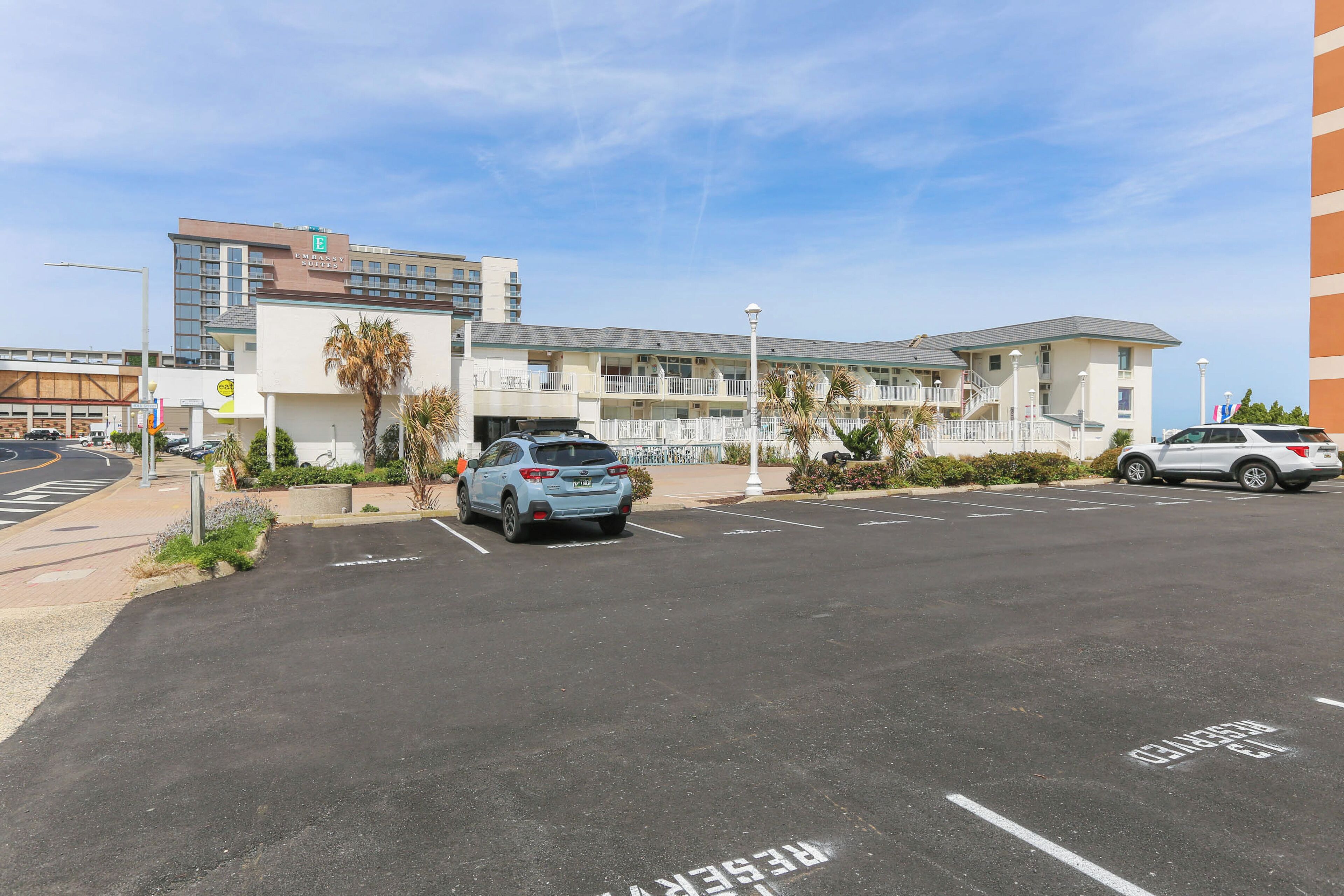 A hotel with a parking lot, a building with multiple floors, and a clear sky.