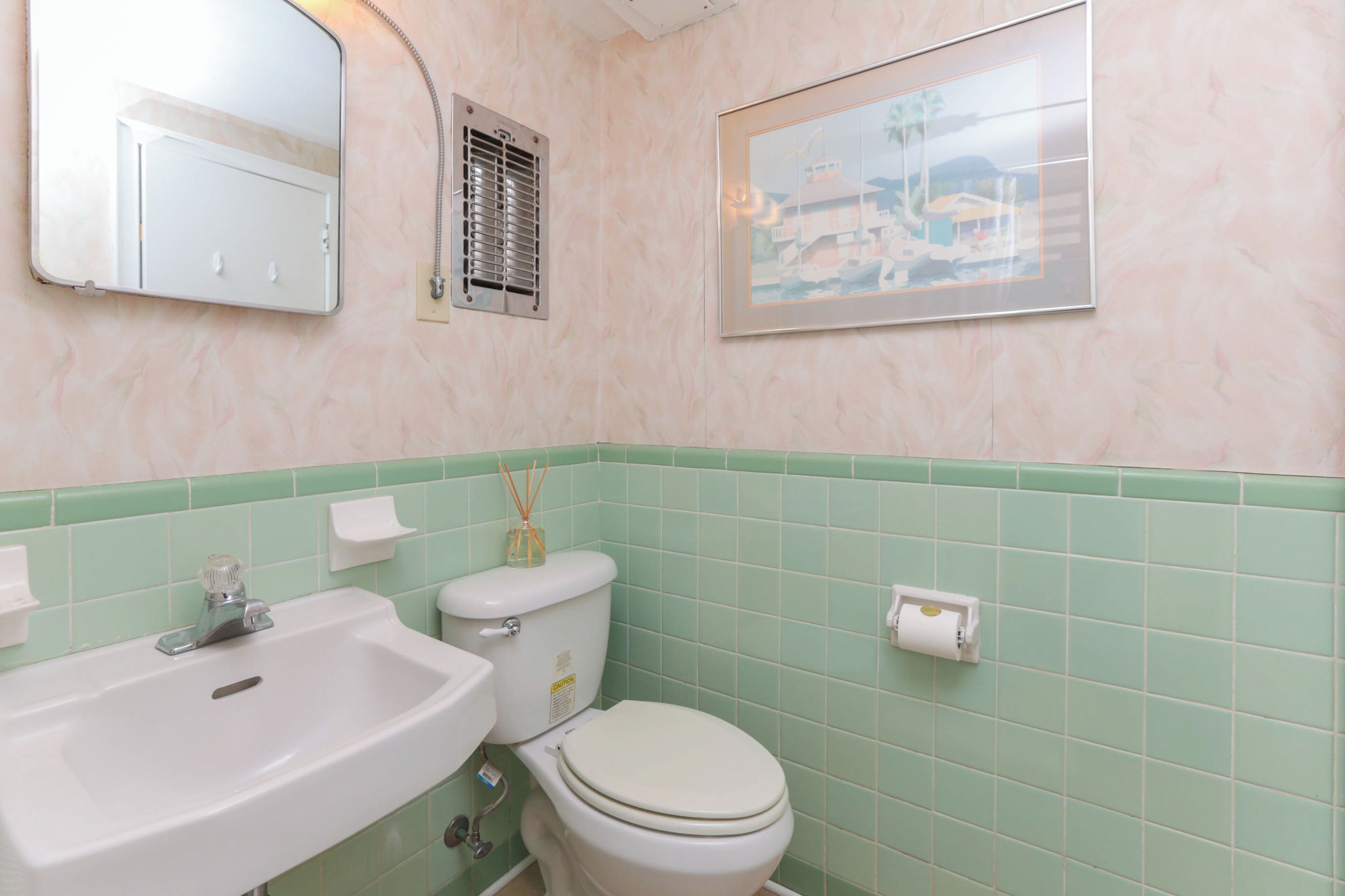A bathroom with a sink, toilet, and a framed picture on the wall.