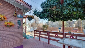 A wooden deck with a table and benches, brick walls, hanging flower baskets, and a sign reading "Your Life Paris". - Close to Midtown! Cozy Reno 'river Cottage' (Reno)