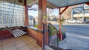 A covered outdoor seating area with a swing chair, a caution sign, and a view of the street. - Half-mi to River Walk: 'rose Cottage' in Truckee! (Reno)