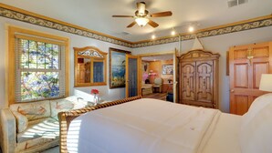 A bedroom with a large bed, a ceiling fan, a wooden wardrobe, a dresser, a chair, and a stained glass window. - Half-mi to River Walk: 'rose Cottage' in Truckee! (Reno)