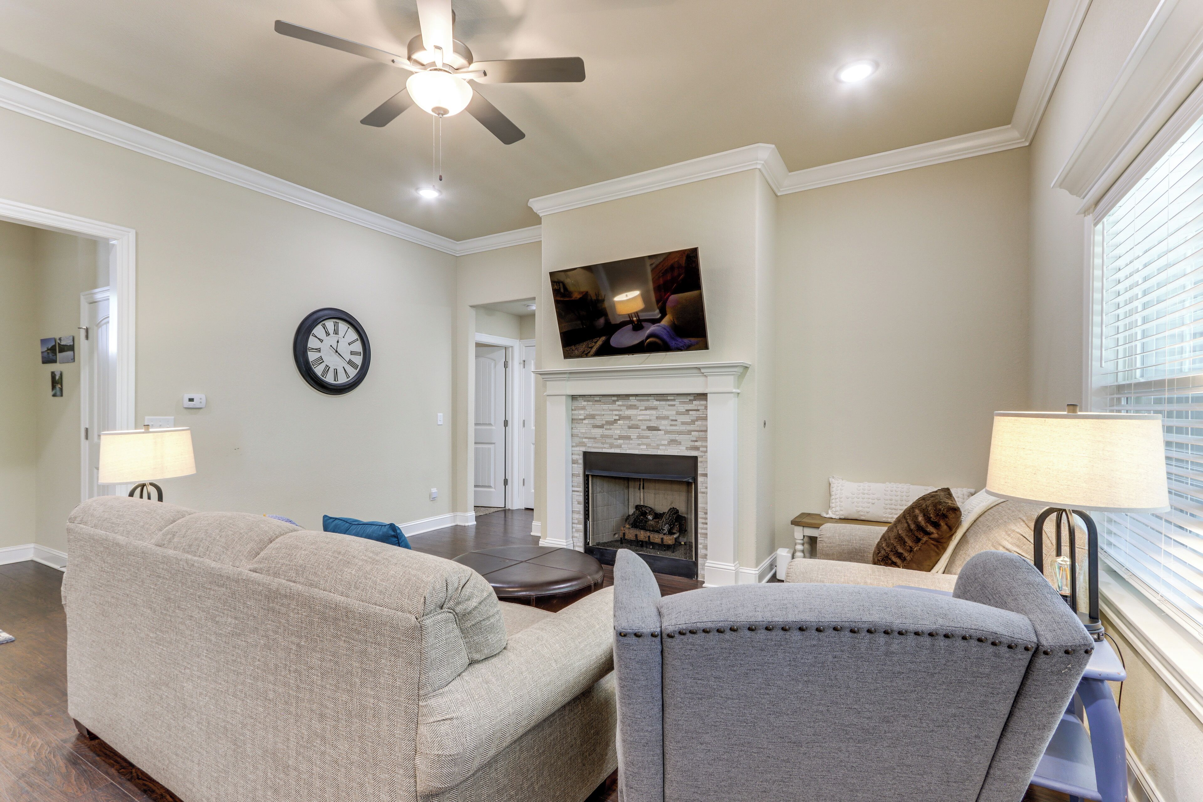 A living room with a fireplace, a ceiling fan, and a television mounted above it.