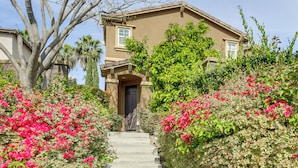 A two-story house with a front entrance, steps leading up to it, and surrounding lush greenery and flowering plants. - 20 Mi to Old Town San Diego: Stay & Play! (Chula Vista)