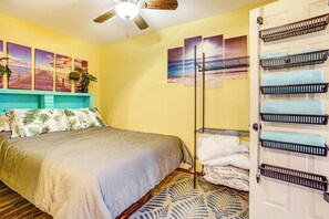 A bedroom with a bed, a ceiling fan, artwork on the wall, and a door with towel racks. - Electric Fireplace: Central Coeur D'alene Studio! (Coeur d'Alene)