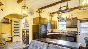 A kitchen with a central island, dark cabinets, and hanging pots. - Electric Fireplace: Central Coeur D'alene Studio! (Coeur d'Alene)
