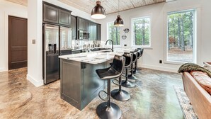 Una cucina moderna con mobili scuri, elettrodomestici in acciaio inossidabile e un'isola centrale con sgabelli da bar.