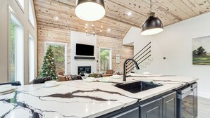 Una cucina moderna con una grande isola, mobili neri e un piano di lavoro in marmo bianco.