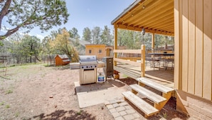 A covered outdoor area with a barbecue grill, picnic tables, and a wooden deck. - Outdoor Entertainment Spaces: Remote Pine Home! (Pine)