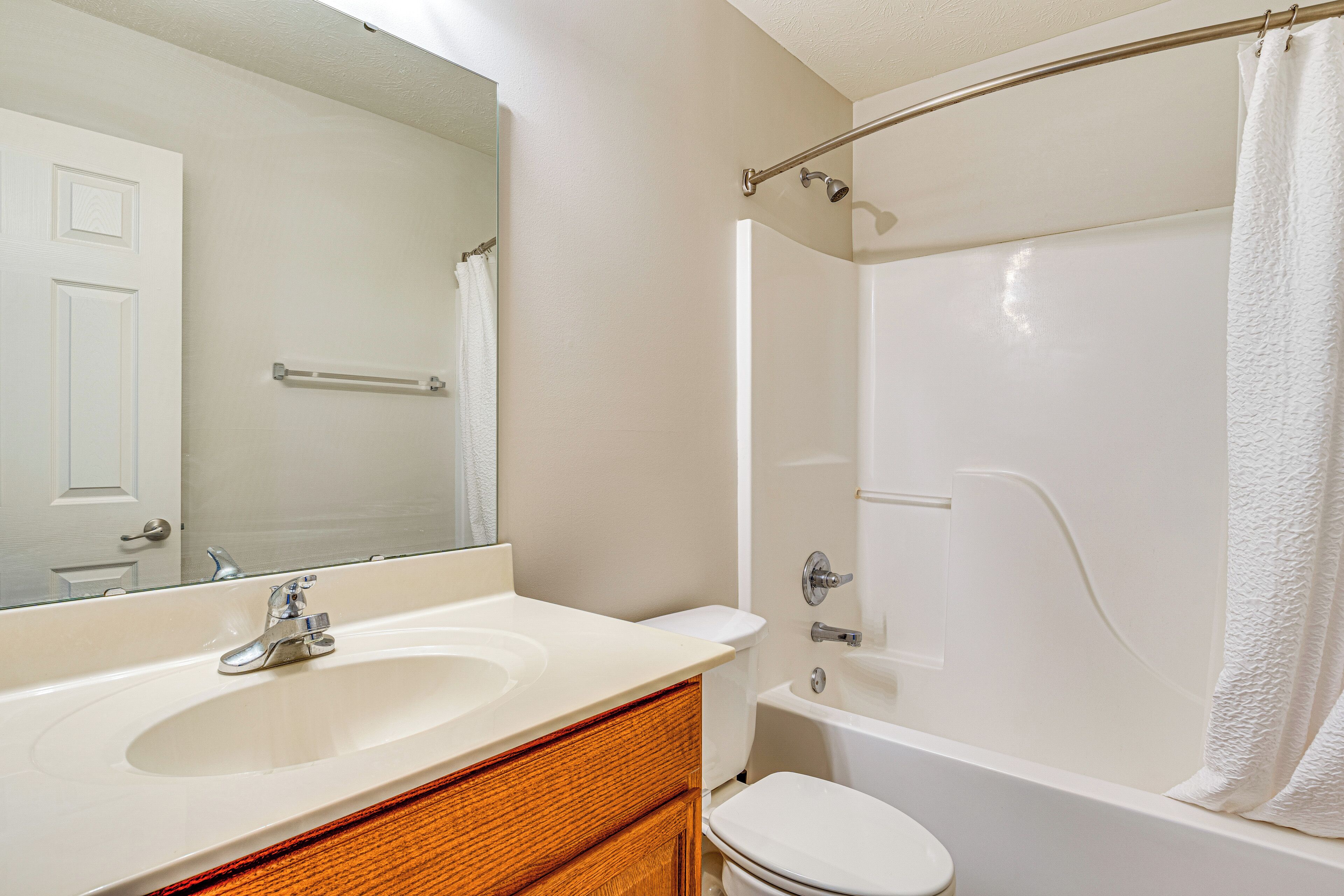 A bathroom with a sink, mirror, toilet, and bathtub.