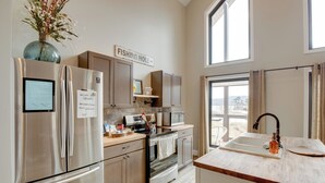 A modern kitchen with stainless steel appliances, a wooden countertop, and a sign reading "FISHING HOLE". - Lakefront Guntersville Apt w/ Shared Dock! (Guntersville)