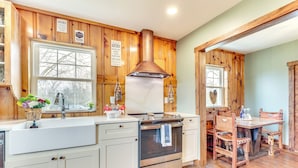 A kitchen with wooden cabinets, a stainless steel range hood, a sink, and a dining table with chairs. - Grill & Fire Pit: New Market Getaway on 3-acres! (New Market)