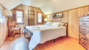 A bedroom with a bed, wooden walls, a chandelier, a window, and a dresser. - Grill & Fire Pit: New Market Getaway on 3-acres! (New Market)