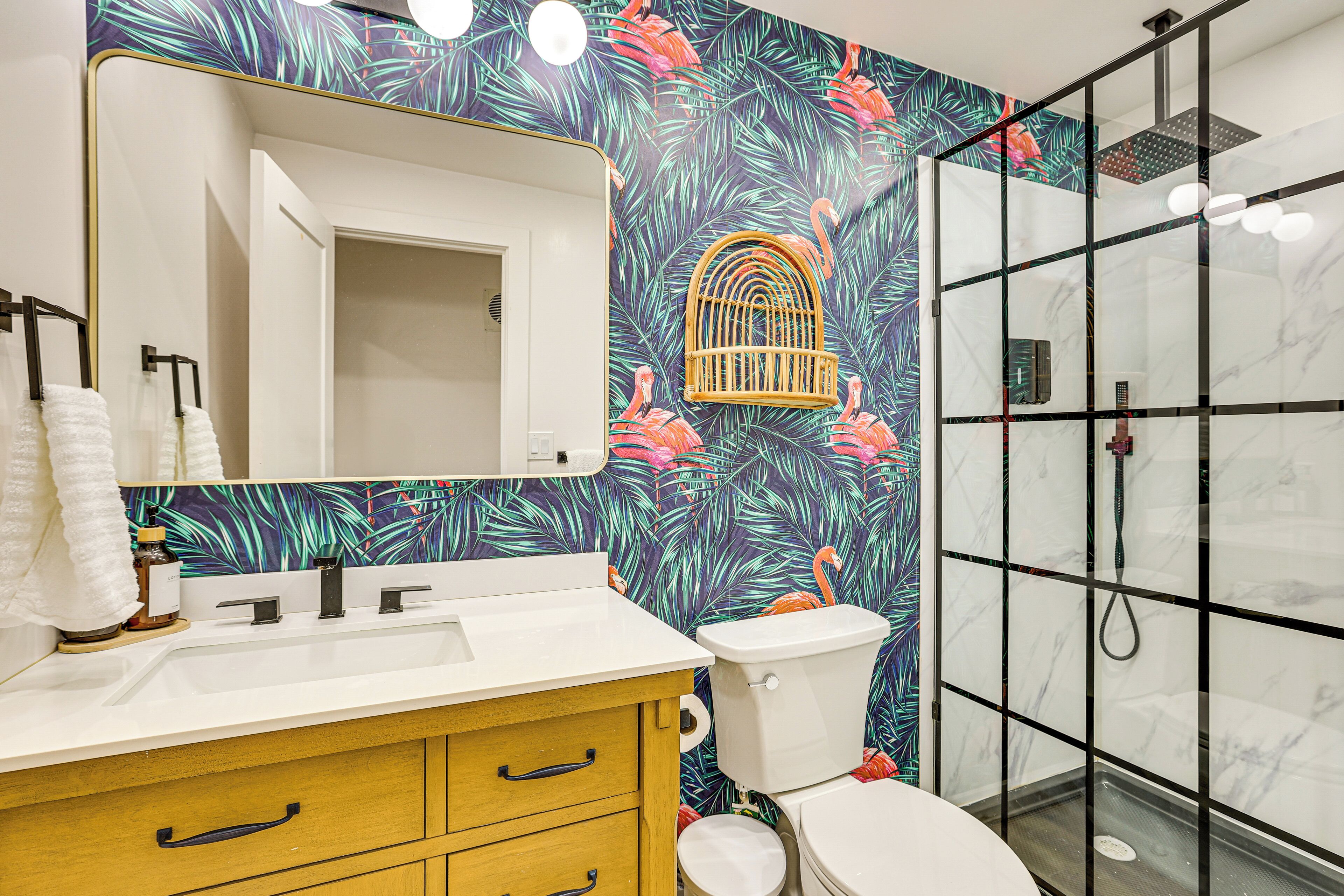 A bathroom with a white sink, wooden vanity, and a glass shower enclosure.