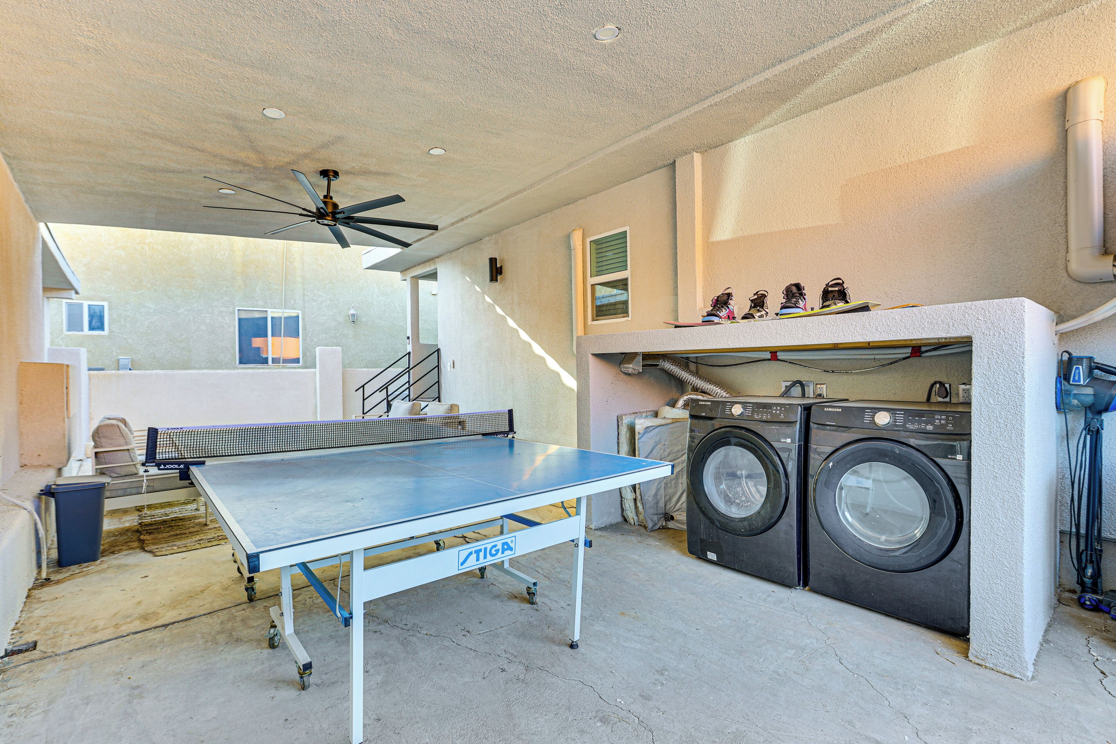 Un'area lavanderia con lavatrice e asciugatrice, una ventola a soffitto e un tavolo da ping pong.