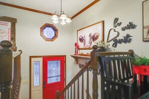 A staircase with a wooden handrail, a red door with a glass panel, and a wall with framed artwork and decorative items. - 34 Mi to Ark Encounter: Kentucky Family Farmhouse (California)