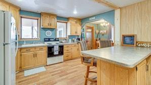 A kitchen with wooden cabinets, a central island, and a dining area.