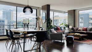 Ein modernes Wohnzimmer mit Essbereich, großen Fenstern und Blick auf die Stadt.