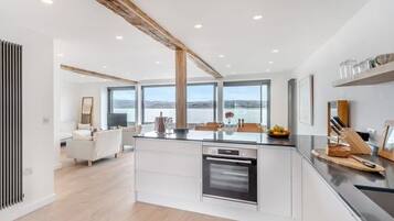 A modern kitchen with a central island, built-in oven, and large windows offering a view of the outdoors.