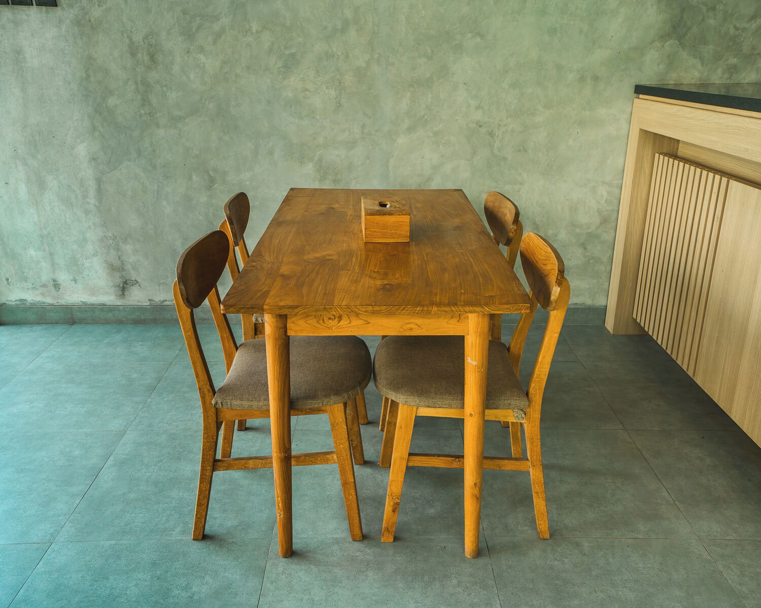 Una mesa de comedor de madera con seis sillas, un mueble de madera y un piso de concreto.