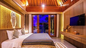 A modern bedroom with a large bed, a television, and a view of the outdoors. - Jero Kelodan Villa (Tabanan)