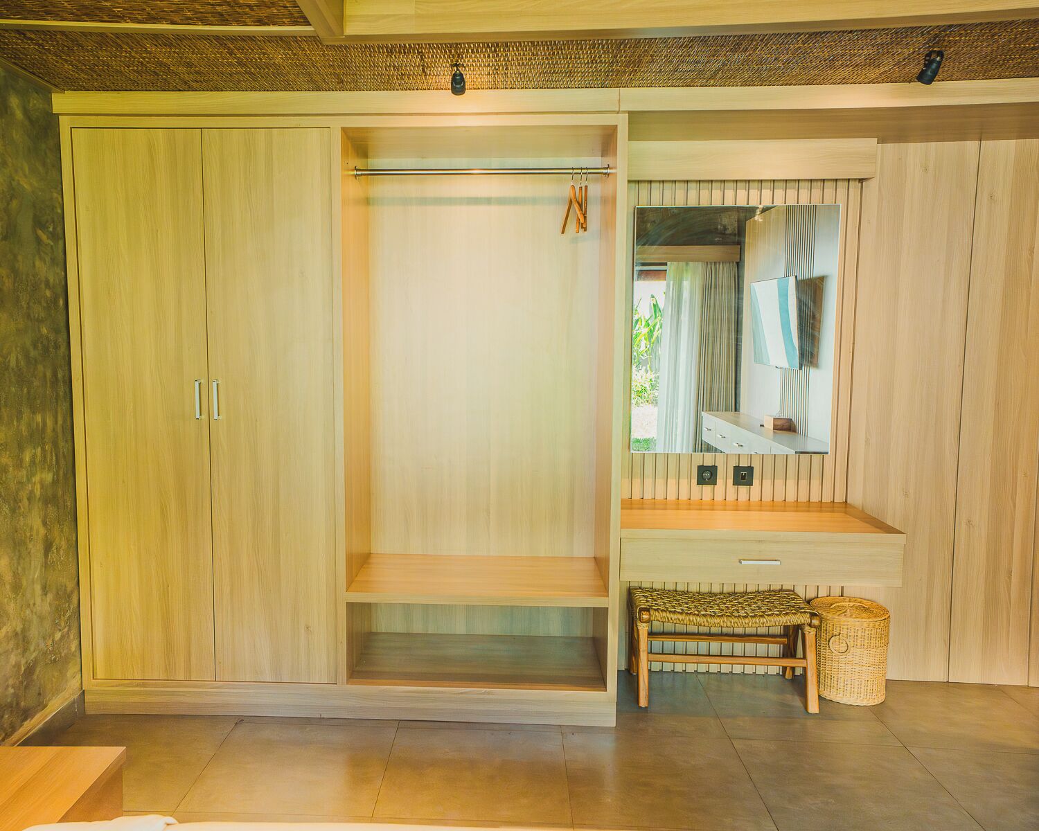 A room with a large wardrobe, a mirror, and a bench.