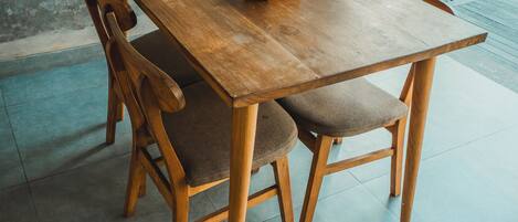 Een houten eettafel met vier stoelen, een notitieboekje en een klein houten doosje op tafel.