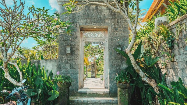 A stone archway leading to a courtyard with a scooter parked nearby. - Jero Kelodan Villa (Tabanan)