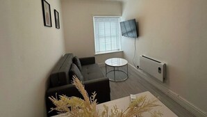 Un salon avec un canapé, une table basse et un téléviseur fixé au mur.