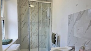 Une salle de bain avec une douche à parois de verre, un lavabo blanc et des toilettes.