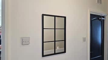 A hallway with a wall-mounted window, a door, and a light switch.
