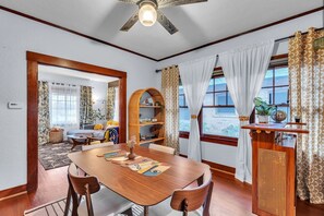 Enjoy meals in this dining area with a table for four, a ceiling fan, and a large window offering a view of the outdoors.