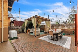 Relax in a serene patio area with a brick patio, pergola, and comfortable seating.