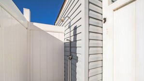 Un mur extérieur blanc, avec un tuyau métallique et une porte.