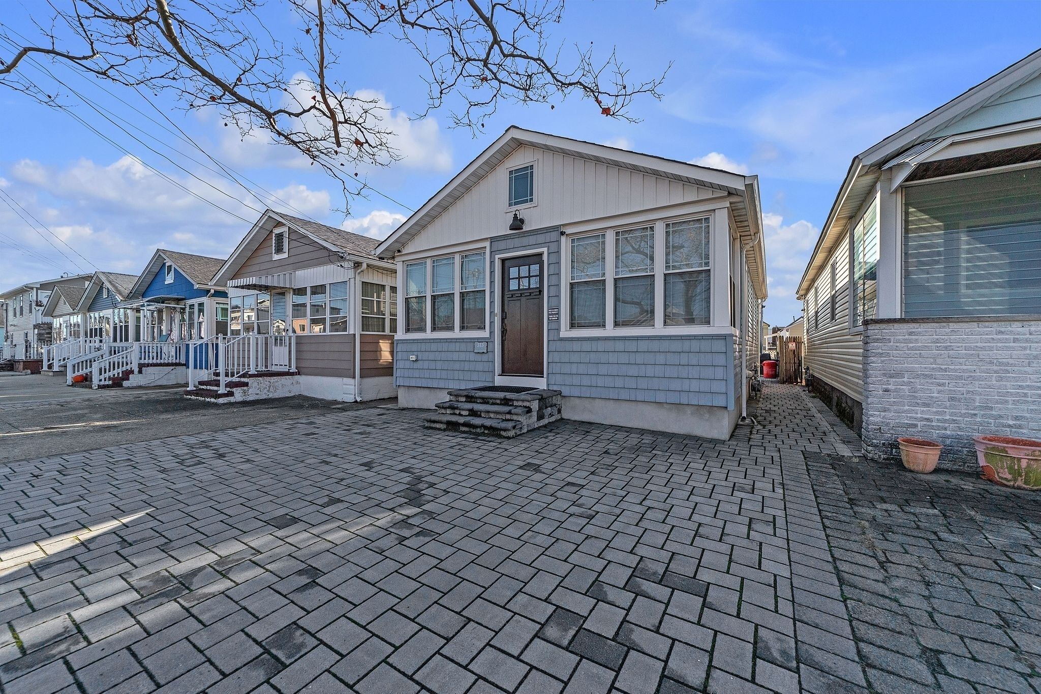 A row of mobile homes with a paved walkway, each with a front porch and a small set of steps leading to the door.