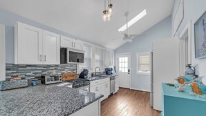 Une cuisine moderne avec des meubles blancs, des plans de travail en granit et un îlot central bleu.