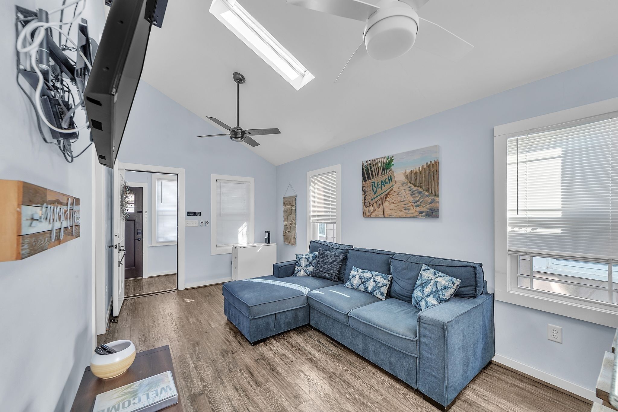 A modern living room with a sectional sofa, ceiling fan, and artwork on the walls.